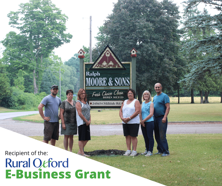 Wilson family gathered around their Ralph Moore & Sons sign at the farm entrance, Recipient of the Rural Oxford E-Business Grant in bottom left of image